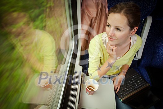 Young woman traveling by train (landscape moving fast behind the window (motion blurred image)