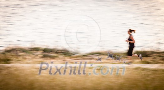 Young woman jogging outdoors (motion blurred image)