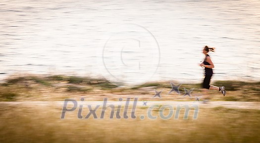 Young woman jogging outdoors (motion blurred image) Young woman jogging outdoors (motion blurred image)