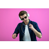 the guy wears glasses and headphones while dancing and having fun isolated on a pink background
