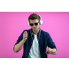 the guy wears glasses and headphones while dancing and having fun isolated on a pink background
