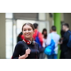 portrait of a happy young student getting ready for class while waiting in the college hallway with headphones and laptop