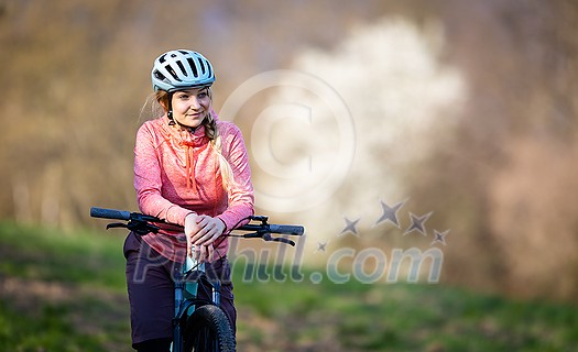 Pretty, young woman with her mountain bike going for a ride past the city limits, getting the daily dose of cardio