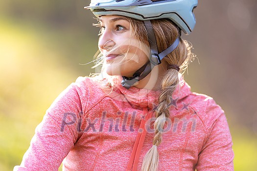 Pretty, young woman with her mountain bike going for a ride past the city limits, getting the daily cardio dose - close-up portrait