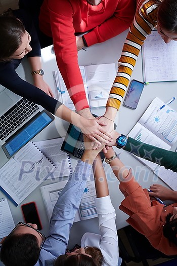 Group of young students in electronics classroom celebrating successfully finished project with holding their hands together, education and technology concept