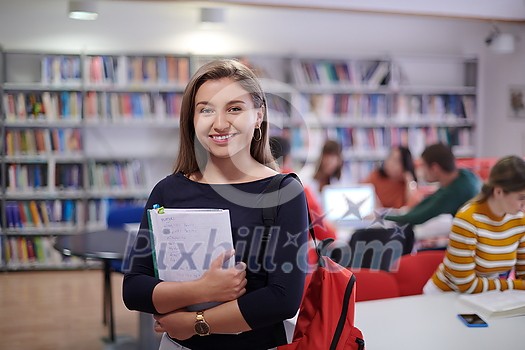 a young student stands with a notebook in front of the library