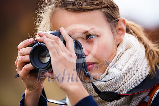 Pretty female amateur photographer taking photos outdoors, doing what she loves to do
