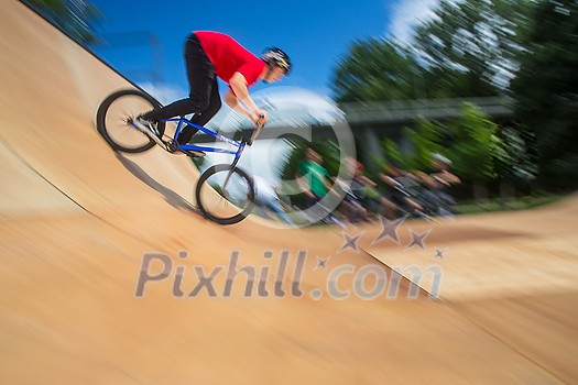 Bmx rider jumping over on a U ramp in a skatepark (motion blurred image)