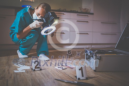 Forensic specialist in protective suit taking photos on a crime scene Forensic specialist in protective suit taking photos on a crime scene