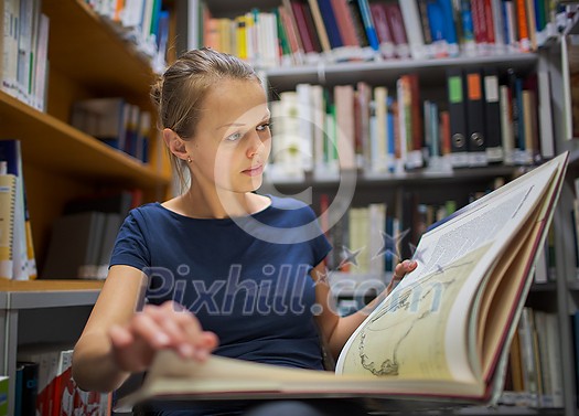 Pretty, young woman studying an old book in archives