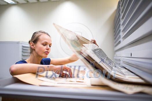Pretty, young woman studying old maps in archives Pretty, young woman studying old maps in archives