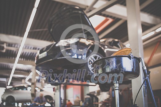 Car in a garage for maintenance, oil/tyre change (shallow DOF; color toned image) Car in a garage for maintenance, oil/tyre change (shallow DOF; color toned image)