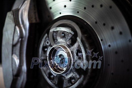 Car in a garage for maintenance, oil, tyre change (shallow DOF; color toned image) - disc brakes detail Car in a garage for maintenance, oil, tyre change (shallow DOF; color toned image) - disc brakes detail