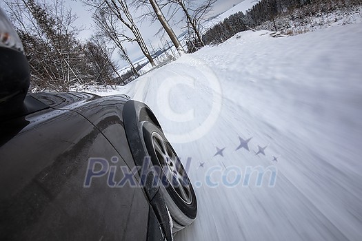 Fast moving car on a winter alpine snowy road