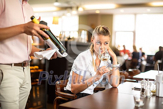 Cute female restaurant customer with wine waiter choosing the right wine for her to go well with the food
