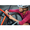 Young woman locking her mountain bike with a numeric lock, setting the code before leaving the bike on a city street (shallow DOF)