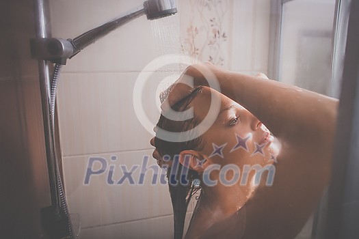 Young woman washing her hair with shampoo, taking a hot long shower