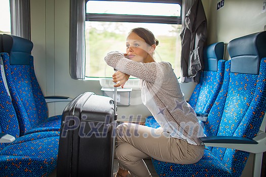 Pretty young woman aboard a train, going for her vacation destination