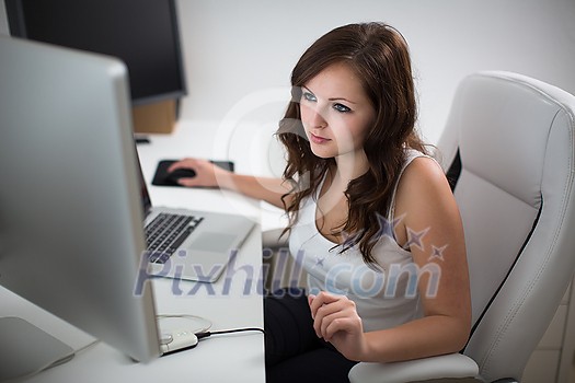 Young woman working on a computer in a home office Young woman working on a computer in a home office