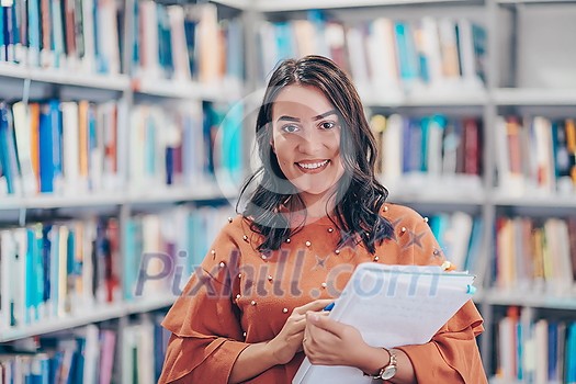 Reading a book in library. Young attractive librarian reading a book between library bookshelves Reading a book in library. Young attractive librarian reading a book between library bookshelves