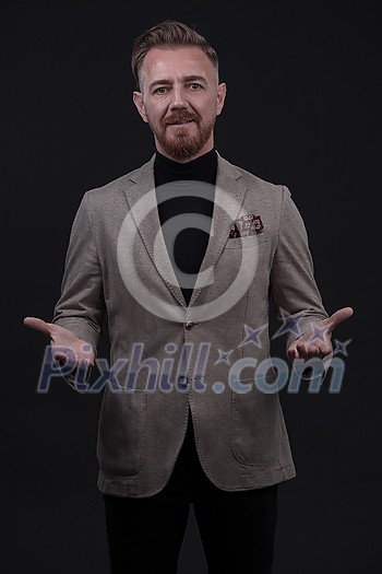 Portrait of a stylish elegant senior businessman with a beard and casual business clothes in photo studio isolated on dark background gesturing with hands. High quality photo