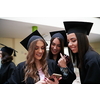 education, graduation, technology and people concept - group of happy international students in mortar boards and bachelor gowns with diplomas using martphone