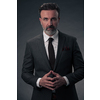 Portrait of a stylish elegant senior businessman with a beard and casual business clothes in photo studio isolated on dark background gesturing with hands. High quality photo