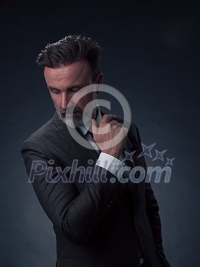 Portrait of a successful stylish elegant senior businessman with a grey beard and casual business clothes confident in photo studio isolated on dark background gesturing with hands. High-quality photo Portrait of a successful stylish elegant senior businessman with a grey beard and casual business clothes confident in photo studio isolated on dark background gesturing with hands. High-quality photo