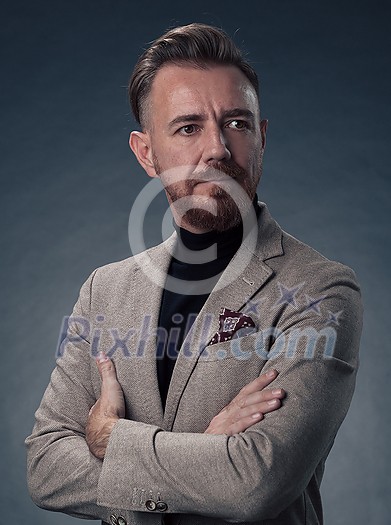 Portrait of a successful stylish elegant senior businessman with a grey beard and casual business clothes confident in photo studio isolated on dark background gesturing with hands. High-quality photo