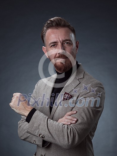 Portrait of a stylish elegant senior businessman with a beard and casual business clothes in photo studio isolated on dark background gesturing with hands. High quality photo