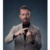 Portrait of a stylish elegant senior businessman with a beard and casual business clothes in photo studio isolated on dark background gesturing with hands. High quality photo