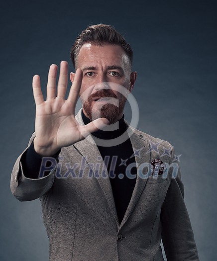 Portrait of a stylish elegant senior businessman with a beard and casual business clothes in photo studio isolated on dark background gesturing with hands. High quality photo