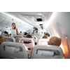 Pretty, young woman aboard an airplane during a lang haul commercial flight - stretching her legs a bit, walking in the aisle