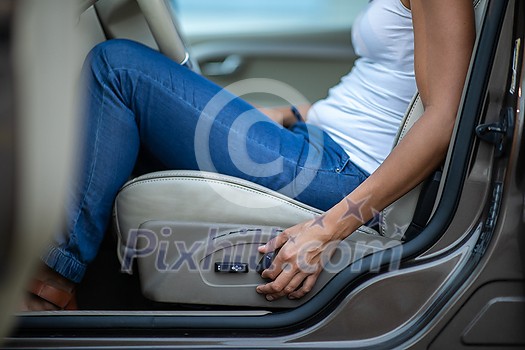 Young female driver driving her car at night (color toned image; shallow DOF) - setting her seat before the ride Young female driver driving her car at night (color toned image; shallow DOF) - setting her seat before the ride