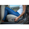 Young female driver driving her car at night (color toned image; shallow DOF) - setting her seat before the ride