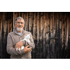 An elderly man holds a cute white kitten and smiles to the camera, selective focus, plenty of copy space