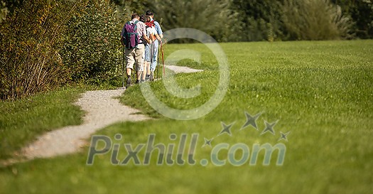 Group of young hikers walk in a row along the road with backpacks on their shoulders