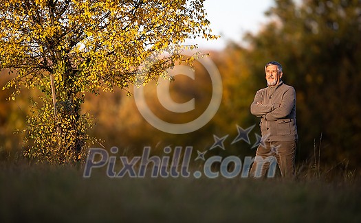 Portrait of handsome senior man in the autumn outdoors. Active senioor enjoying his retirement in the  nature