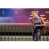 Pretty, young female commuter waiting for her daily train in a modern trainstation, using her cellphone while waiting (color toned image)