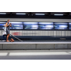 Pretty, young female commuter waiting for her daily train in a modern trainstation, using her cellphone while waiting (color toned image)