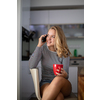 Teenage girl calling on her cell phone while having a cup of tea in modern kitchen setting (shalllow DOF, color toned image)