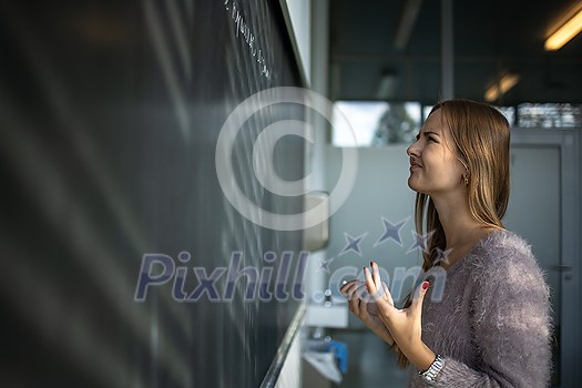 Pretty, young female student in front of a blackboard during math class Pretty, young female student in front of a blackboard during math class