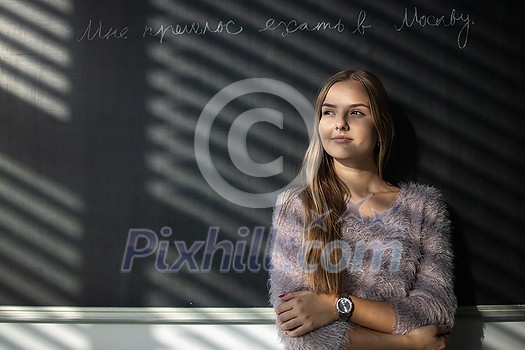 Pretty, young female student in front of a blackboard during class