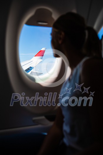 Young woman looking out of the window during a flight on a commercial aircraft