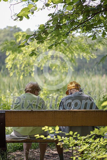 Elderly couple outdoors in summer. Happy elderly couple on a walk. Handsome man and woman senior citizens. Husband and wife of old age against the background of nature.