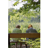 Elderly couple outdoors in summer. Happy elderly couple on a walk. Handsome man and woman senior citizens. Husband and wife of old age against the background of nature.