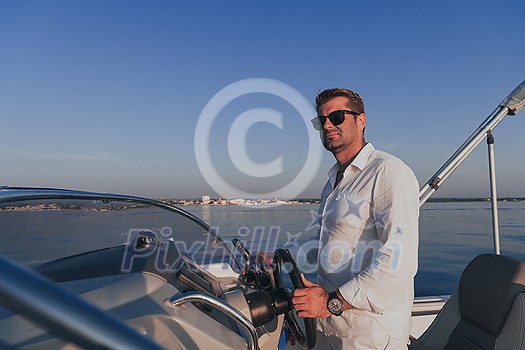 A determined senior businessman in casual clothes and sunglasses enjoys his vacation driving a luxury boat at sunset. Selective focus. High-quality photo