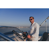 A determined senior businessman in casual clothes and sunglasses enjoys his vacation driving a luxury boat at sunset. Selective focus. High-quality photo