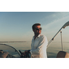 A determined senior businessman in casual clothes and sunglasses enjoys his vacation driving a luxury boat at sunset. Selective focus. High-quality photo