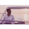 A determined senior businessman in casual clothes and sunglasses enjoys his vacation driving a luxury boat at sunset. Selective focus. High-quality photo